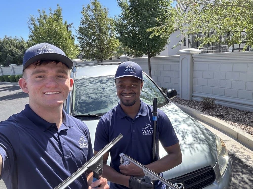 Two Wave Window Cleaning technicians in uniform holding squeegees