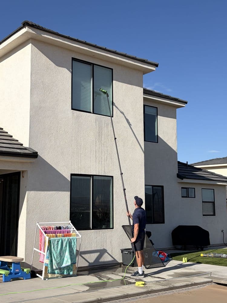 Technician cleaning second-story windows with a waterfed pole